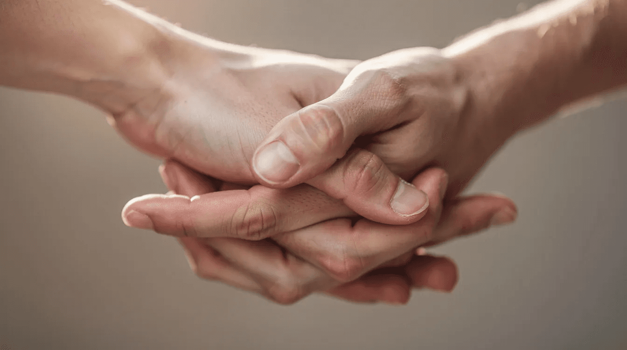 A close-up image shows two hands gently clasped together, symbolizing comfort and support, reflecting the principles of trauma informed care. This gesture emphasizes the importance of mutuality and empowerment in mental health services for trauma survivors.