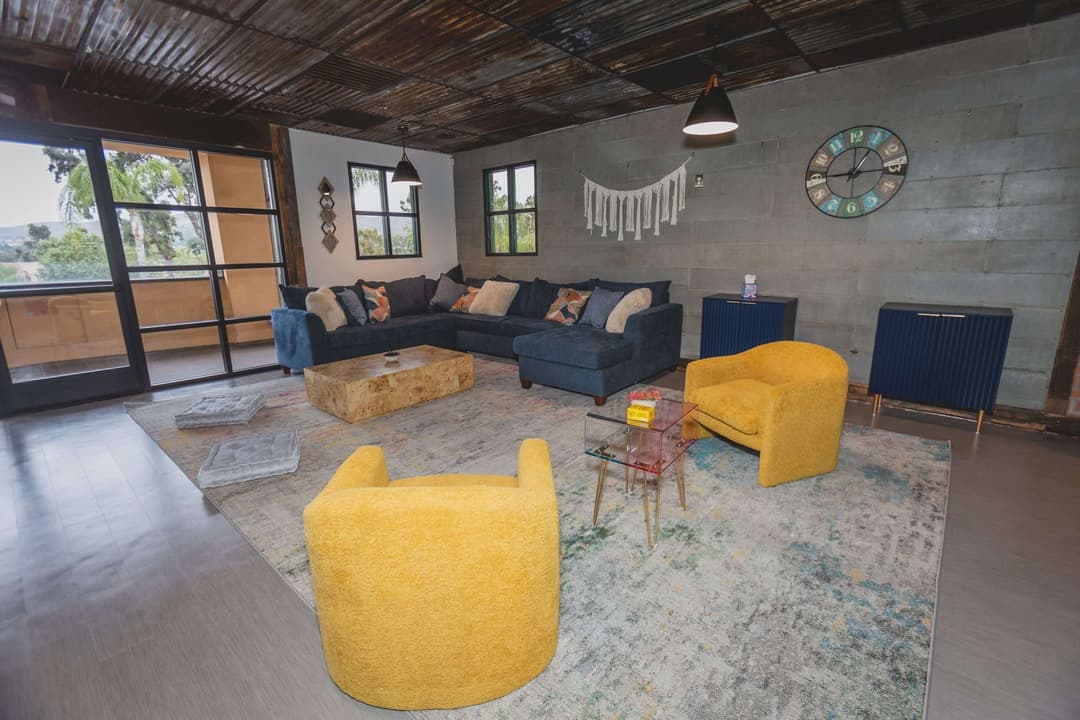 Living room with a navy sectional sofa, yellow armchairs, and a patterned rug