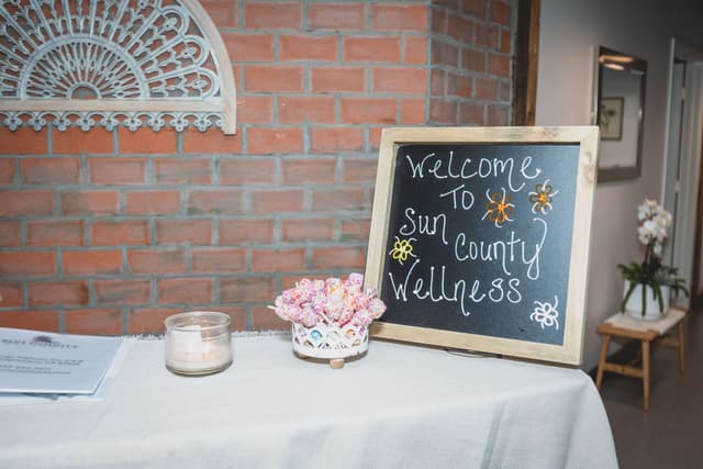 Chalkboard sign at the front table that reads Welcome to Sun County Wellness