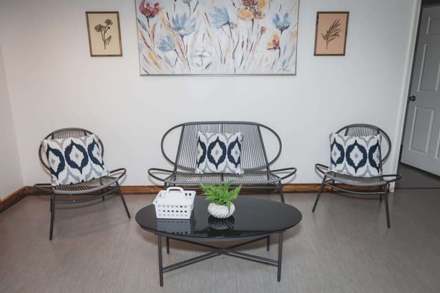 Sitting area with woven chairs, blue pillows, and floral wall art